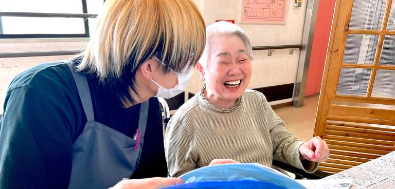 スタッフと入居者がレクリエーション活動を楽しむ様子。笑顔で交流している。